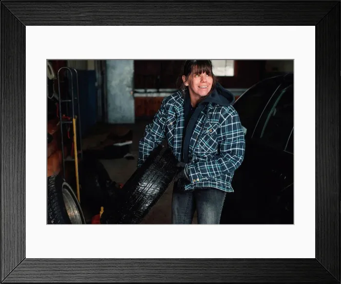 Framed Print : Woman carrying tyre in workshop