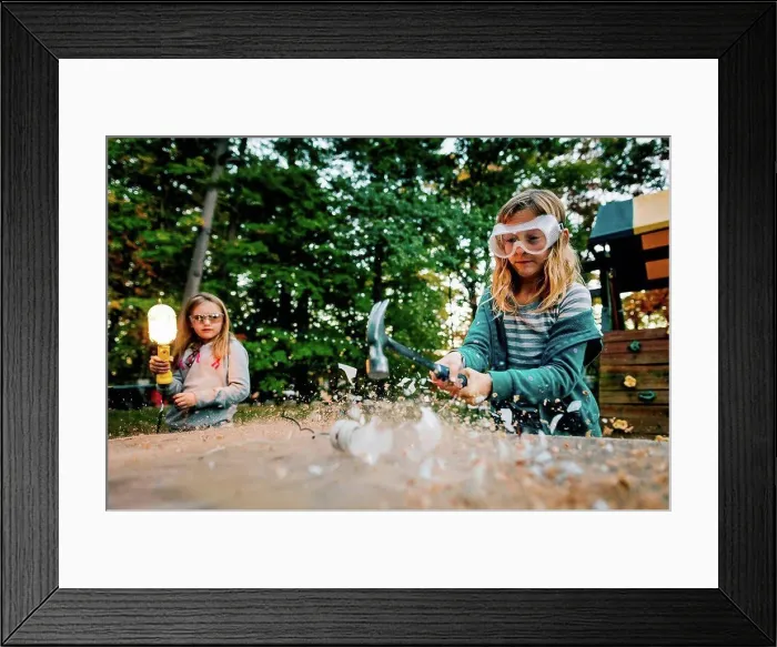 Framed Print : Girl smashing lightbulb with hammer on garden table at dusk