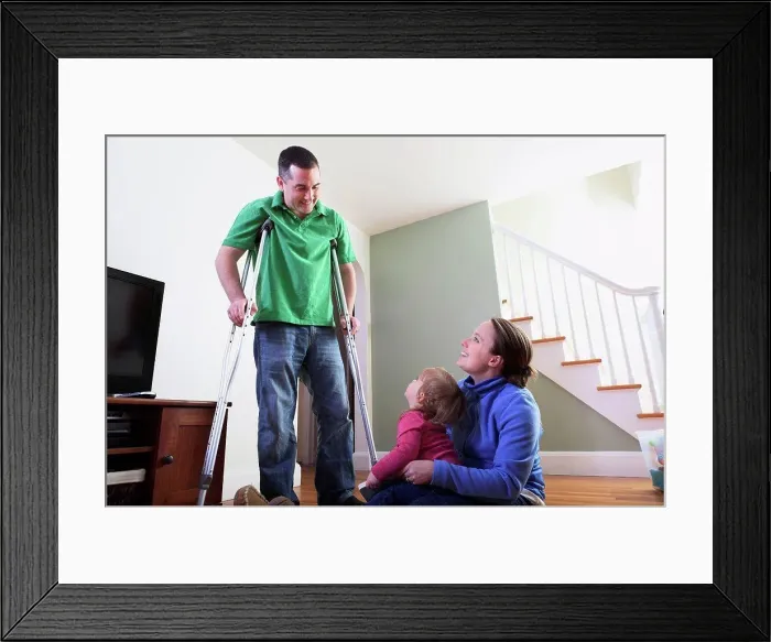Framed Print : Man after anterior cruciate ligament (ACL) surgery with wife and daughter at home