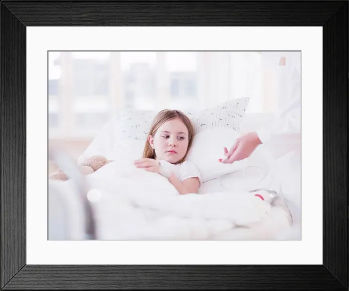 Framed Print : A young girl with brown hair lying in bed, a needle fixed to her hand and a female medic setting up a drip Framed Print : A young girl with brown hair lying in bed, a needle fixed to her hand and a female medic setting up a drip