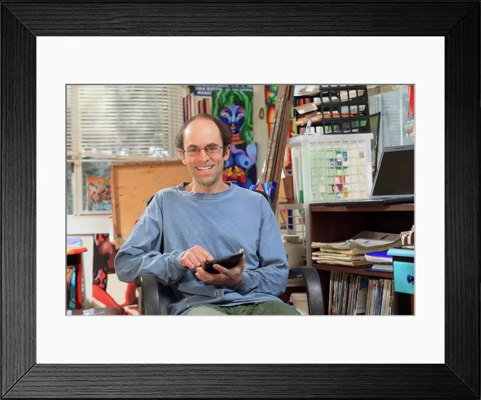 Framed Print : Man with Asperger's working on his tablet in his art studio Framed Print : Man with Asperger's working on his tablet in his art studio