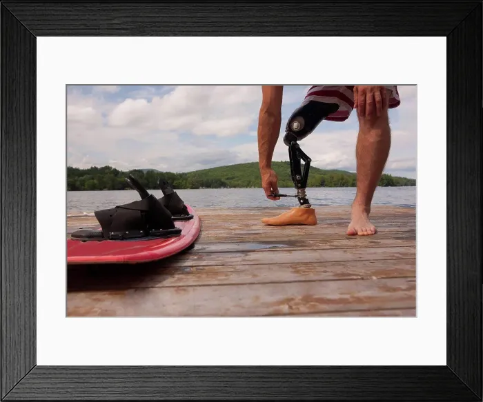 Framed Print : Athlete adjusting his artificial leg on a dock
