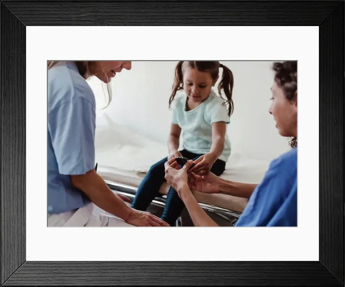Framed Print : Healthcare worker showing glaucometer to girl by doctor in clinic Framed Print : Healthcare worker showing glaucometer to girl by doctor in clinic
