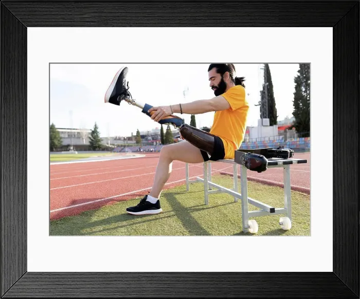 Framed Print : Bearded man removing prosthetic leg sitting on bench Framed Print : Bearded man removing prosthetic leg sitting on bench