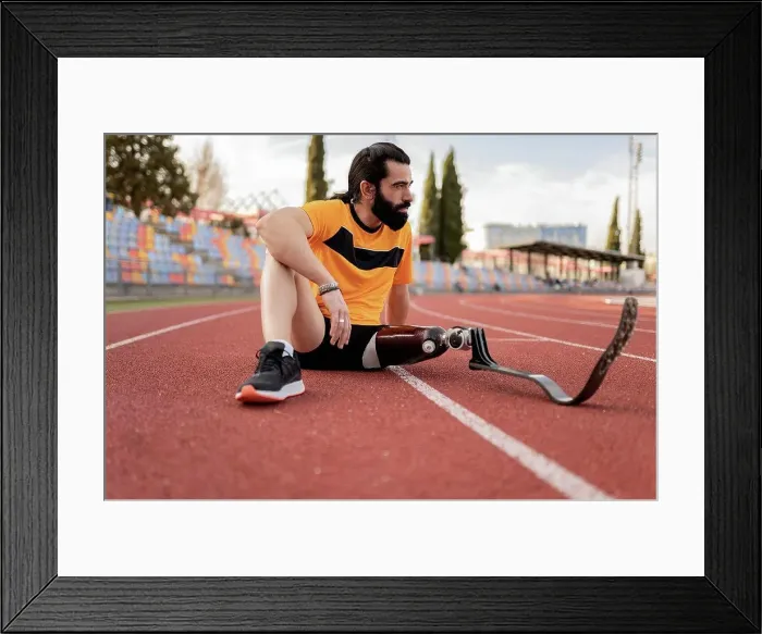 Framed Print : Athlete with prosthetic leg sitting on running track