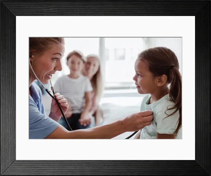 Framed Print : Female pediatrician listening to girl's heartbeat through stethoscope at clinic Framed Print : Female pediatrician listening to girl's heartbeat through stethoscope at clinic