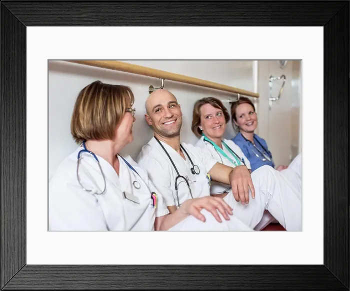 Framed Print : Happy male doctor and female colleagues leaning together on wall in hospital Framed Print : Happy male doctor and female colleagues leaning together on wall in hospital