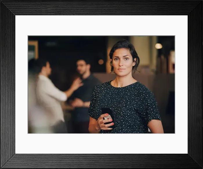 Framed Print : Portrait of confident businesswoman holding mobile phone in creative office Framed Print : Portrait of confident businesswoman holding mobile phone in creative office