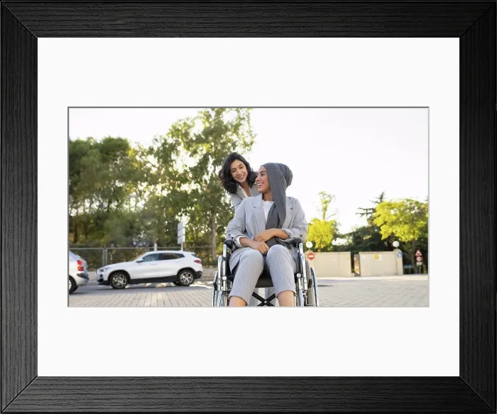Framed Print : Happy businesswoman talking with disabled female colleague on footpath Framed Print : Happy businesswoman talking with disabled female colleague on footpath