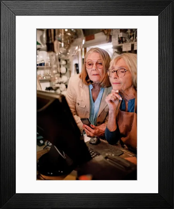 Framed Print : Senior female customer and saleswoman looking at computer monitor in hardware store Framed Print : Senior female customer and saleswoman looking at computer monitor in hardware store