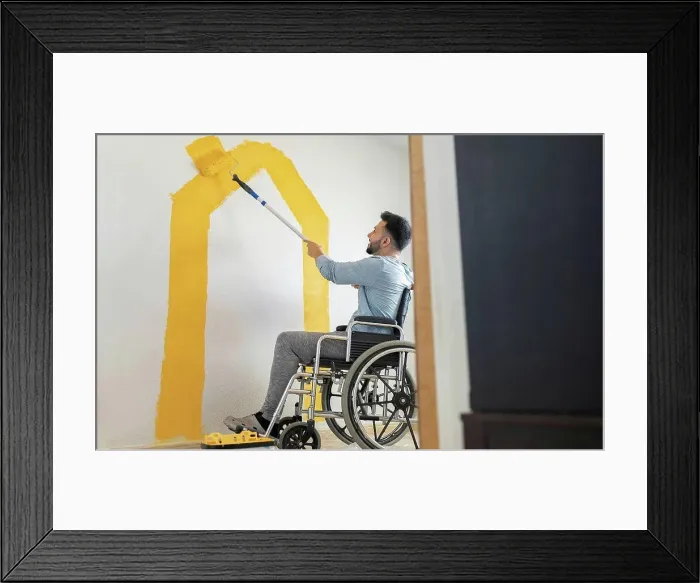 Framed Print : Man with disability painting wall through paint roller at home Framed Print : Man with disability painting wall through paint roller at home