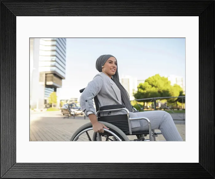 Framed Print : Smiling disabled woman sitting on wheelchair at footpath Framed Print : Smiling disabled woman sitting on wheelchair at footpath