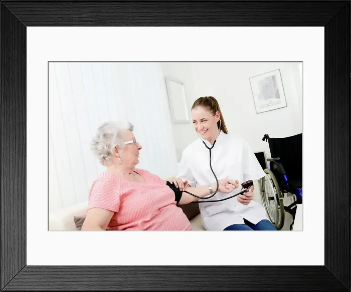 Framed Print : Elderly senior woman with young doctor having medical care at home Framed Print : Elderly senior woman with young doctor having medical care at home