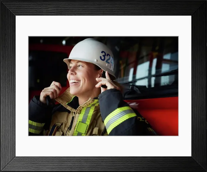 Framed Print : Smiling female firefighter wearing helmet at fire station Framed Print : Smiling female firefighter wearing helmet at fire station