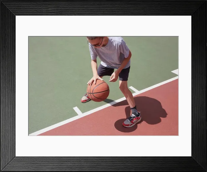 Framed Print : Boy (8-9) dribbling basketball in park Framed Print : Boy (8-9) dribbling basketball in park