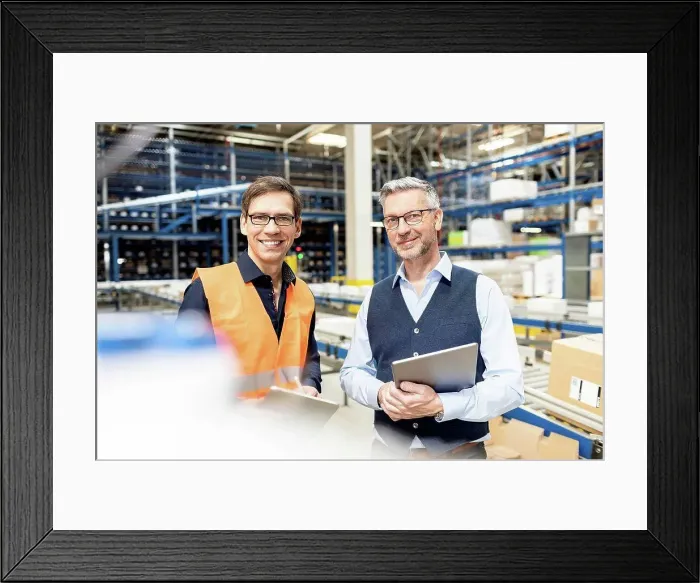 Framed Print : Happy worker standing by manager holding tablet PC in warehouse Framed Print : Happy worker standing by manager holding tablet PC in warehouse