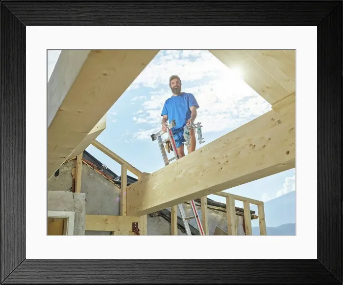 Framed Print : Young man standing on ladder at construction site