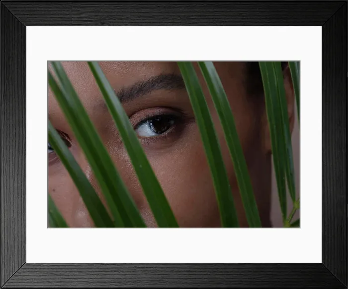 Framed Print : Studio portrait of woman behind palm leaf Framed Print : Studio portrait of woman behind palm leaf