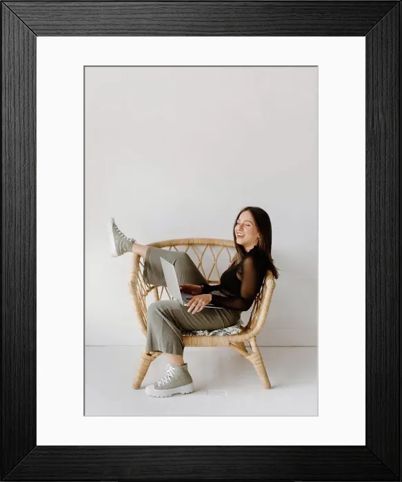 Framed Print : Young woman sitting in chair with laptop Framed Print : Young woman sitting in chair with laptop