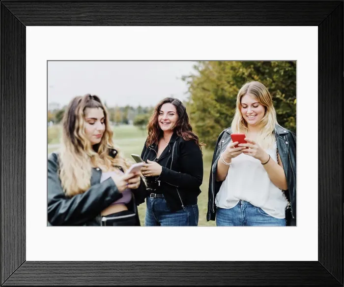 Framed Print : Three young women using their phones in park Framed Print : Three young women using their phones in park