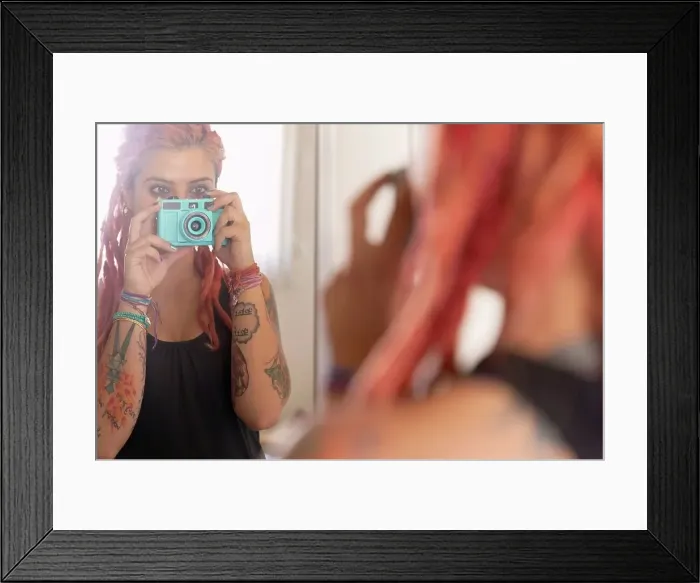 Framed Print : Over shoulder mirror view of young woman with pink dreadlocks taking selfie Framed Print : Over shoulder mirror view of young woman with pink dreadlocks taking selfie