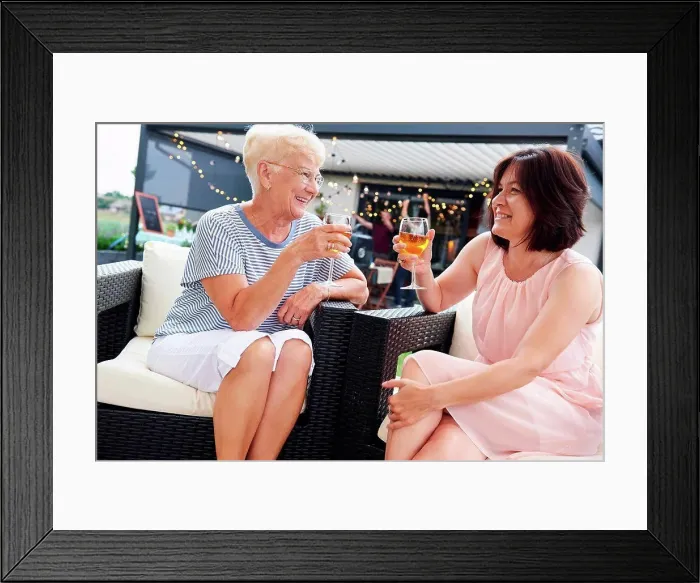Framed Print : Senior and mature women raising a wine toast at family lunch on patio