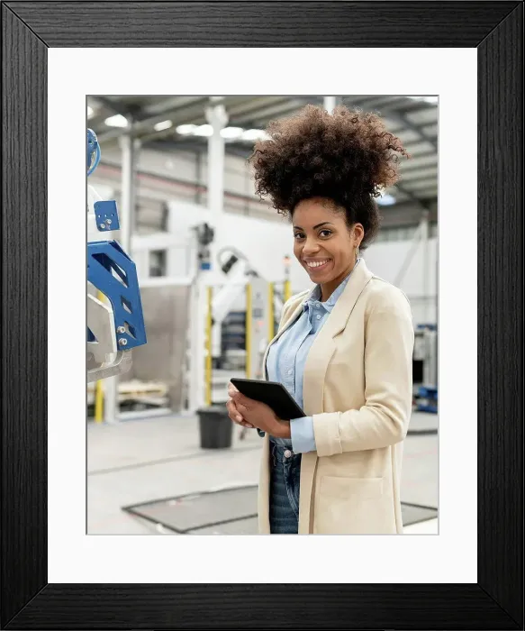 Framed Print : Happy businesswoman holding tablet PC standing in factory Framed Print : Happy businesswoman holding tablet PC standing in factory