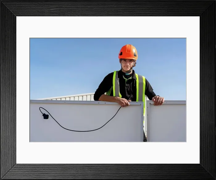 Framed Print : Technician with helmet standing by solar panel