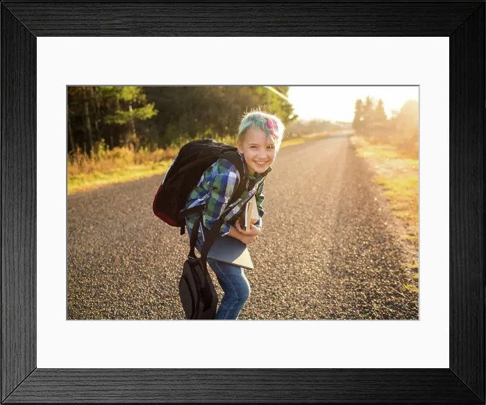 Framed Print : Canada, Ontario, Smiling boy (8-9) with books on rural road at sunset Framed Print : Canada, Ontario, Smiling boy (8-9) with books on rural road at sunset