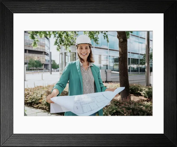 Framed Print : Happy architect wearing hardhat standing with construction plan Framed Print : Happy architect wearing hardhat standing with construction plan