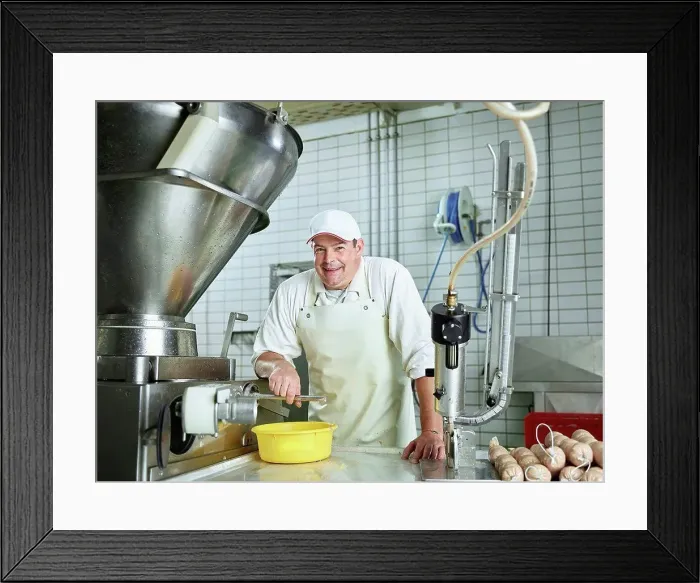 Framed Print : Happy butcher standing by machinery in factory Framed Print : Happy butcher standing by machinery in factory