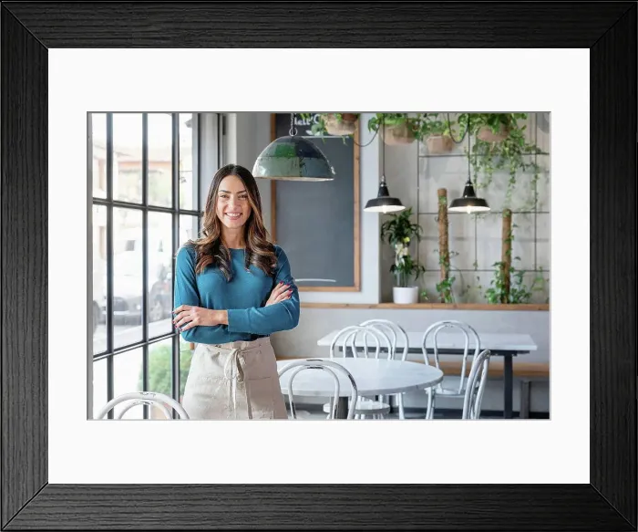 Framed Print : Smiling woman standing with arms crossed in cafe Framed Print : Smiling woman standing with arms crossed in cafe
