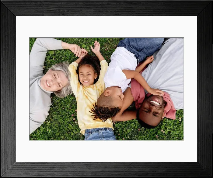 Framed Print : Smiling family resting together on grass