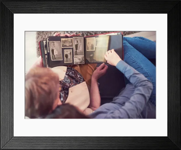 Framed Print : Overhead view of young woman on sofa with grandmother looking at photo album Framed Print : Overhead view of young woman on sofa with grandmother looking at photo album