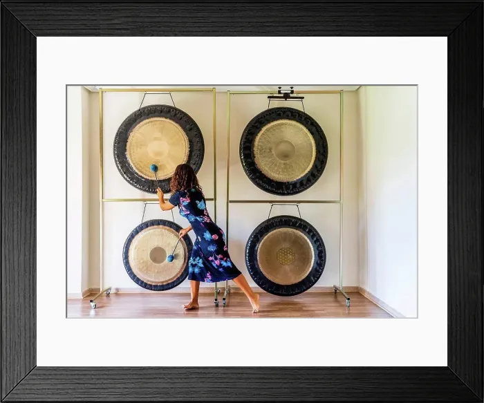 Framed Print : Female sound therapist playing gongs with mallets in studio Framed Print : Female sound therapist playing gongs with mallets in studio