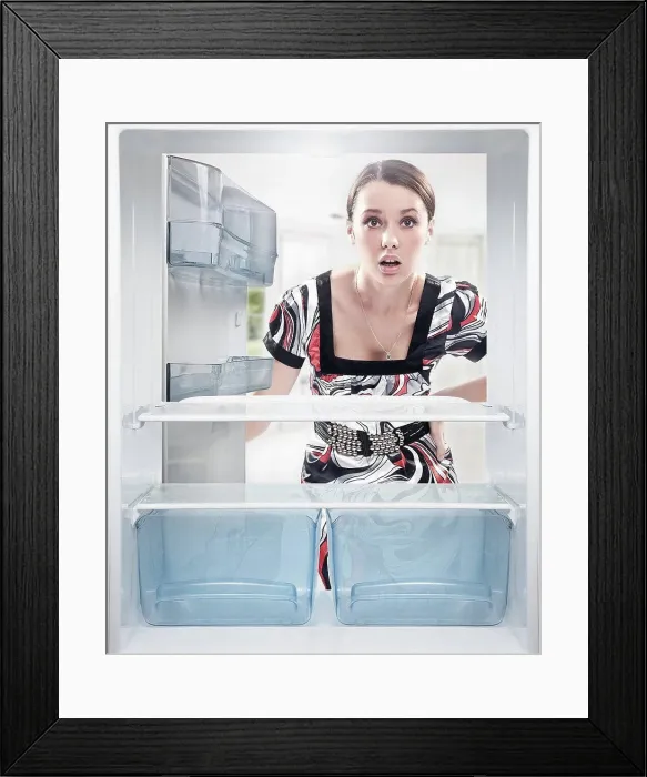 Framed Print : Young woman looking on empty shelf in fridge