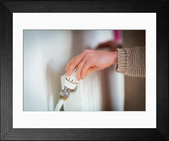 Framed Print : Woman adjusting a thermostatic radiator valve on a domestic radiator Framed Print : Woman adjusting a thermostatic radiator valve on a domestic radiator