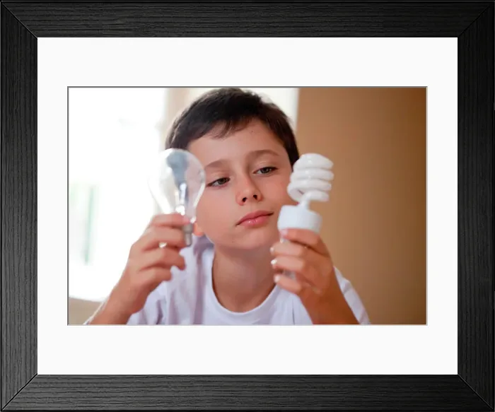 Framed Print : Boy holding energy saving lightbulb (right) and incandescent lightbulb (left) Framed Print : Boy holding energy saving lightbulb (right) and incandescent lightbulb (left)