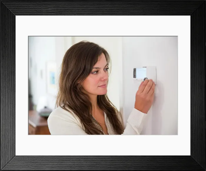 Framed Print : Woman setting a thermostat Framed Print : Woman setting a thermostat