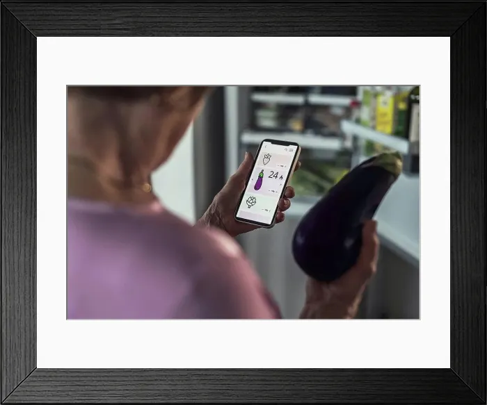 Framed Print : Woman counting calories through smart phone app at home Framed Print : Woman counting calories through smart phone app at home