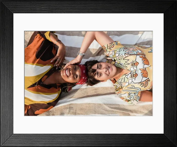 Framed Print : Woman touching lesbian friend lying on picnic blanket at beach Framed Print : Woman touching lesbian friend lying on picnic blanket at beach