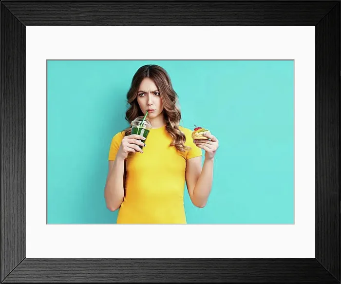 Framed Print : Unhappy woman on dieting drinking detox juice holding cake in hand choosing healthy food. Diet concept. eating lifestyle Framed Print : Unhappy woman on dieting drinking detox juice holding cake in hand choosing healthy food. Diet concept. eating lifestyle
