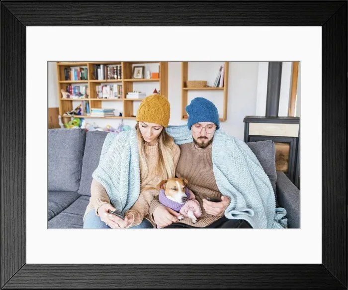 Framed Print : Couple with dog sitting on couch wrapped in blanket looking at smartphone Framed Print : Couple with dog sitting on couch wrapped in blanket looking at smartphone