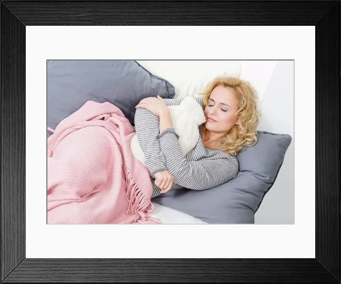 Framed Print : Woman lying on couch with hot water bottle Framed Print : Woman lying on couch with hot water bottle