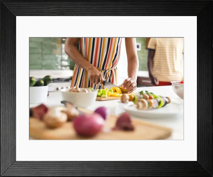 Framed Print : Biracial woman in a striped dress is chopping vegetables in a kitchen Framed Print : Biracial woman in a striped dress is chopping vegetables in a kitchen