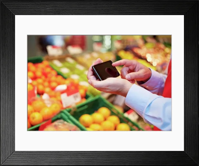 Framed Print : Germany, Cologne, Mature man using smart phone in supermarket Framed Print : Germany, Cologne, Mature man using smart phone in supermarket
