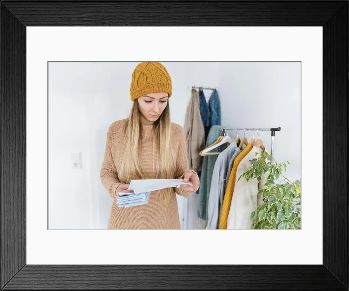 Framed Print : Woman with wooly checking bills standing in dressing room Framed Print : Woman with wooly checking bills standing in dressing room