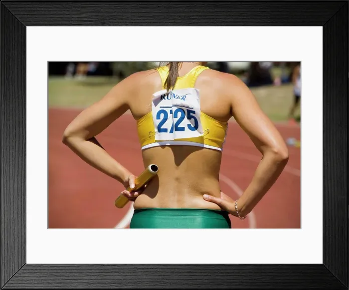 Framed Print : Female athlete holding a relay baton at the beginning of a race Framed Print : Female athlete holding a relay baton at the beginning of a race