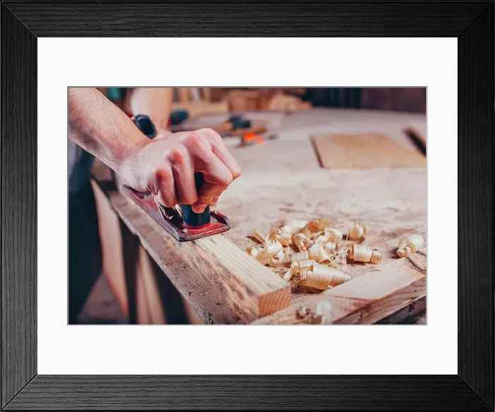 Framed Print : Midsection of carpenter planing wood at workshop Framed Print : Midsection of carpenter planing wood at workshop