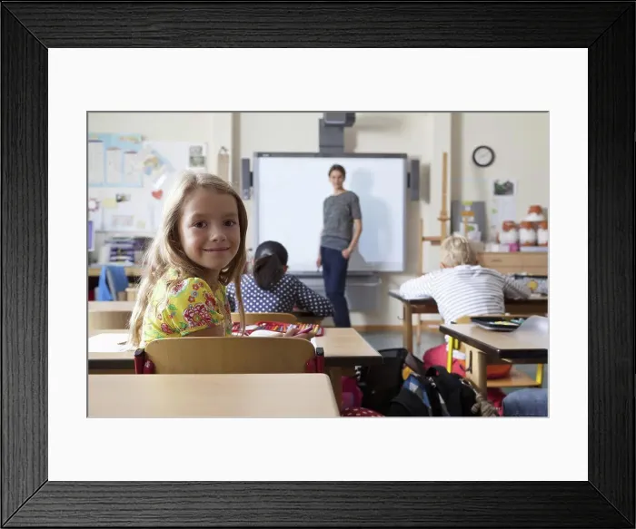 Framed Print : Girl sitting in classroom, smiling Framed Print : Girl sitting in classroom, smiling
